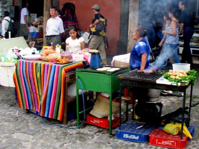 A street vendor in Antigua, Guatemala selling pupusas, roasted meat and other foods.